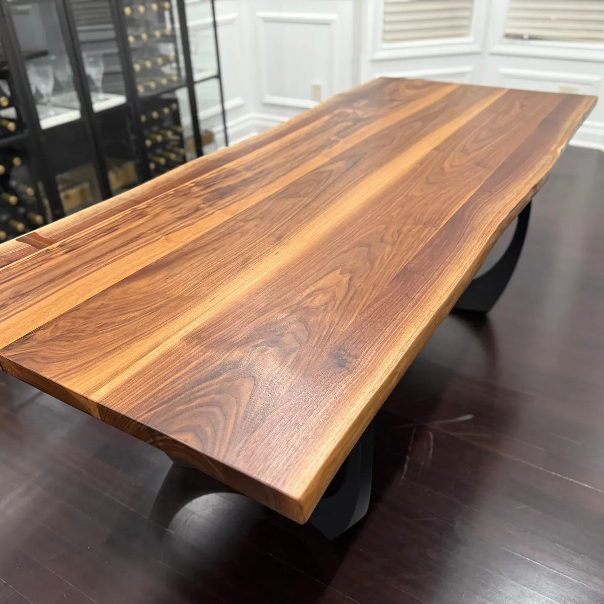 Wooden dining table in a room with a window and shelves.