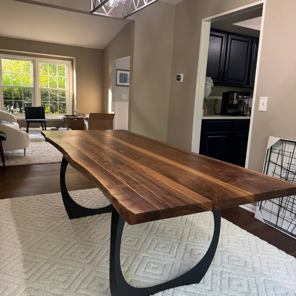 Wooden dining table in a home setting with a kitchen in the background
