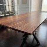 Side angle of a custom walnut dining table showcasing smooth finish and steel base