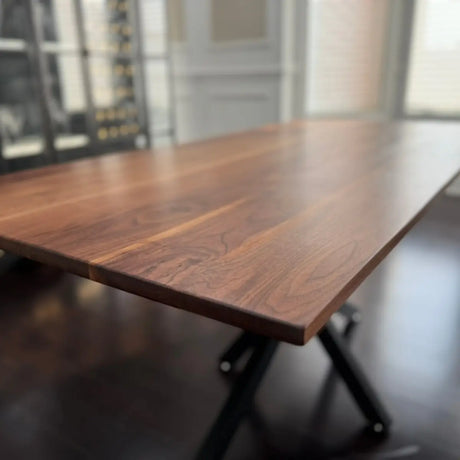 Side angle of a custom walnut dining table showcasing smooth finish and steel base